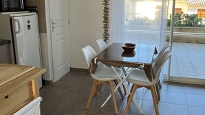 Une cuisine compacte équipée d’un four à micro-ondes, d’un petit réfrigérateur et d’un coin repas avec une table et des chaises.