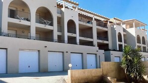 Un hôtel à plusieurs étages doté de balcons, d’un espace extérieur couvert et d’un parking souterrain.