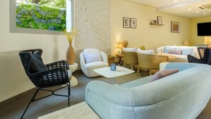 A modern living room with a large window, wicker furniture, and a view of greenery outside. - B&B HOTEL Antibes Juan-les-Pins (Antibes)