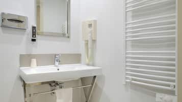 Une salle de bain moderne avec un lavabo blanc, un miroir, un porte-serviettes et une serviette qui y est suspendue.