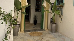 De ingang van Hotel Dar Al Madina met een betegelde binnentuin, planten in potten en een bord boven de ingang.