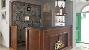 Een ruime keuken met een houten eiland, een betegelde vloer met patroon en hangende rieten lampenkappen.