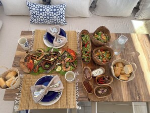 Une table à manger avec des fruits de mer, des salades, du pain et des condiments.