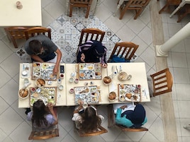 A dining area with a tiled floor, wooden chairs, and a table set with various dishes.