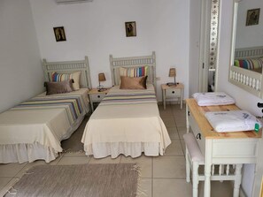 Une chambre avec deux lits, un bureau et un miroir.