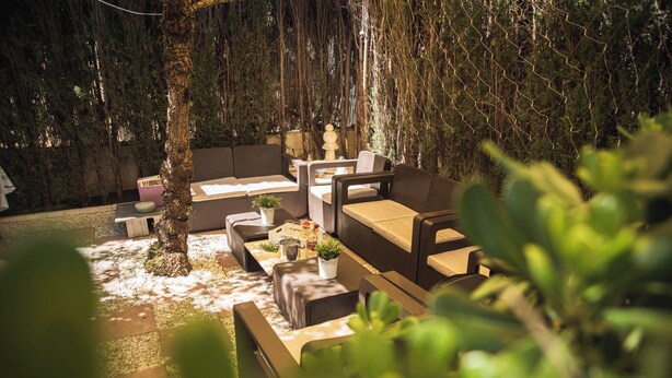 An outdoor seating area with sofas and tables, surrounded by trees and greenery. - Villa del Mamut, en Padul Granada (PADUL)