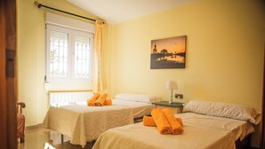 A hotel room with two beds, a window with curtains, a painting on the wall, and a nightstand with a lamp. - Villa del Mamut, en Padul Granada (PADUL)