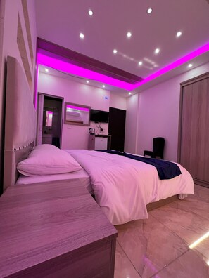 A modern bedroom with a bed, bedside table, and a TV mounted on the wall. - Petra Heaven (Wadi Musa)