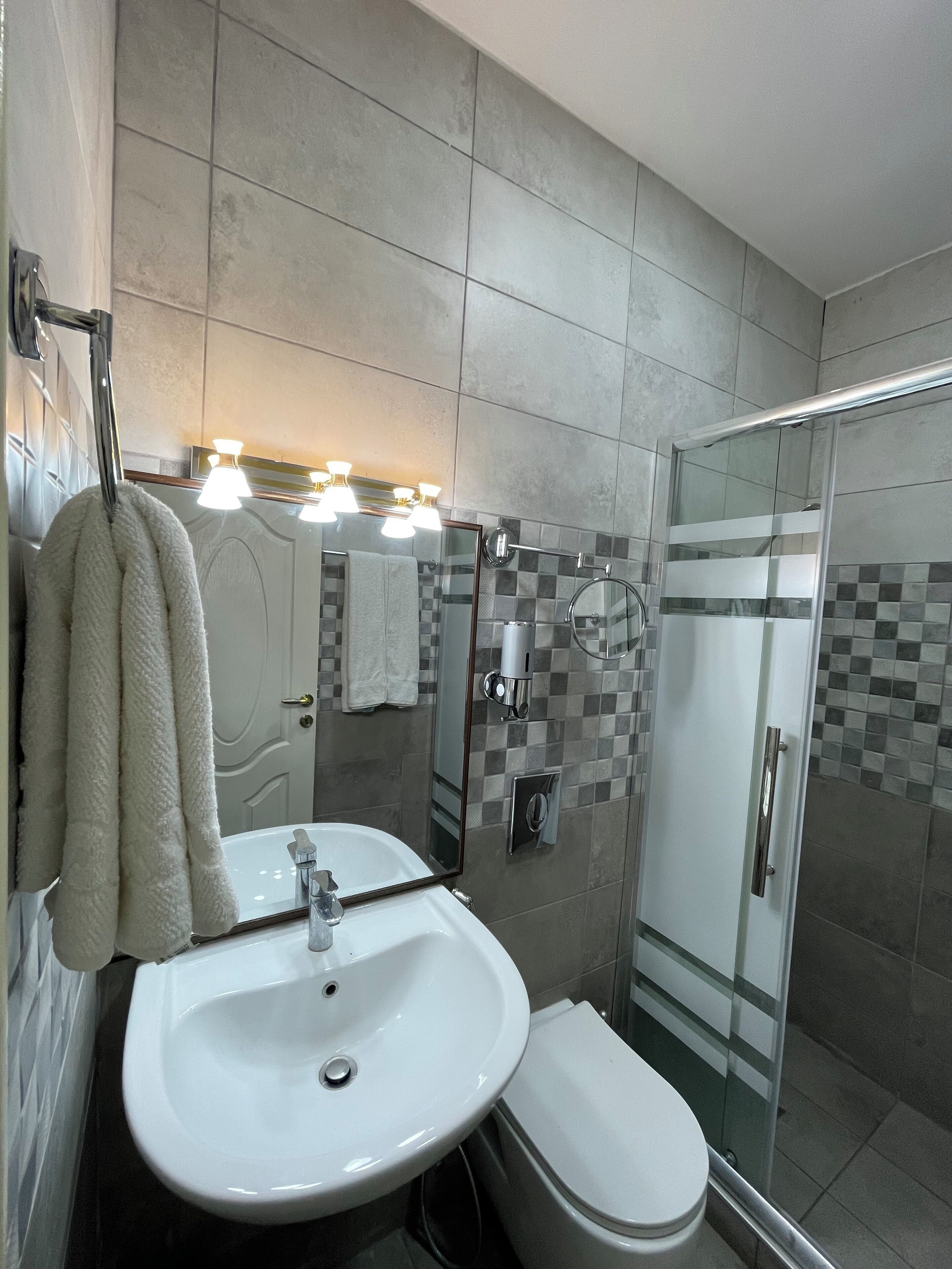 A bathroom with a white sink, toilet, and glass shower enclosure.
