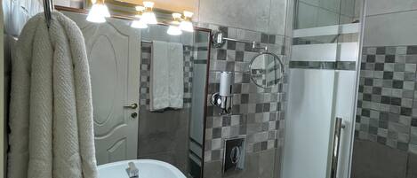A bathroom with a white sink, toilet, and glass shower enclosure.
