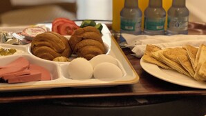 A breakfast tray with eggs, ham, pastries, and juice bottles. - Petra Heaven (Wadi Musa)