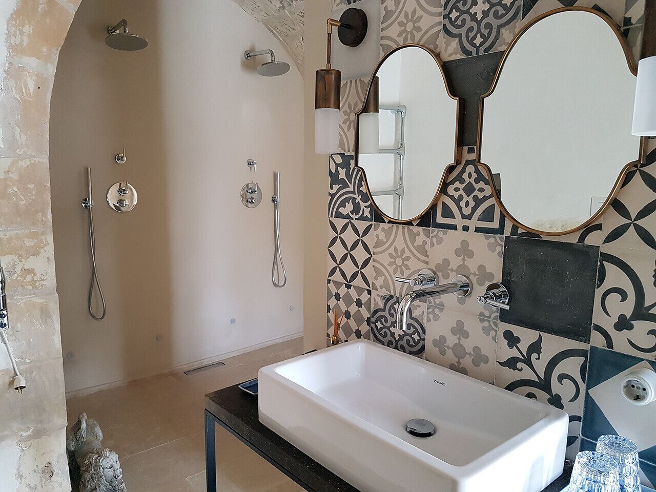 A bathroom with a white sink, a shower, and a mirror.