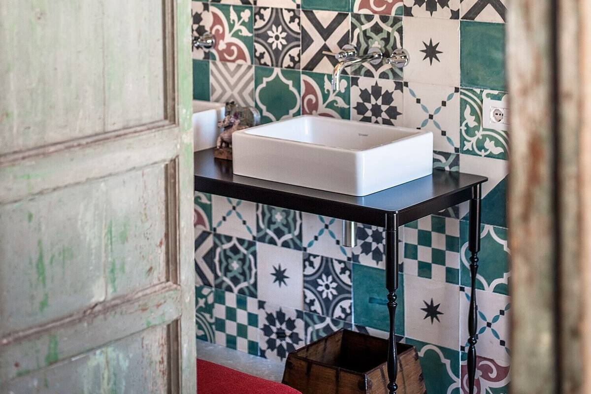 A bathroom with a sink, mirror, and patterned tiles.