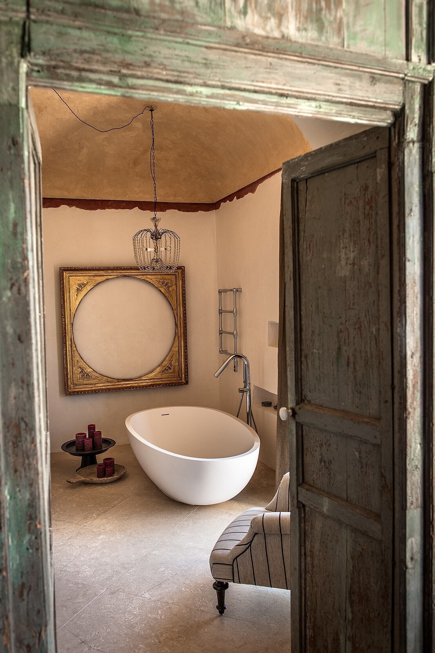 Un bagno con una vasca freestanding, uno specchio grande e un lampadario.