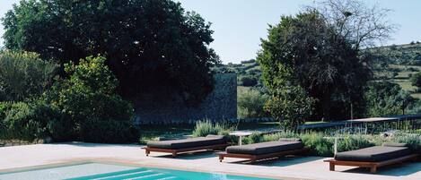 Alberca al aire libre, sombrillas en la alberca y camastros