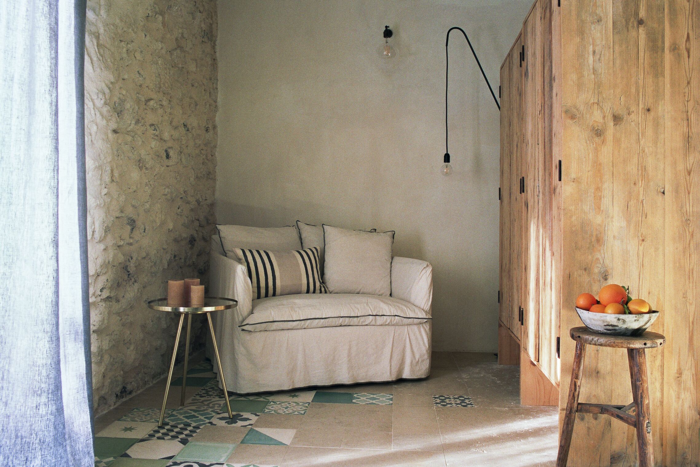 A cozy room with a sofa, a small table with candles, and a bowl of fruit on a stool.