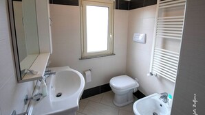 Une salle de bain équipée d’un lavabo, d’un bidet, de toilettes et d’un miroir.