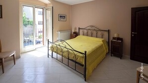 Une chambre à coucher avec un lit, une chaise, une table de chevet, une porte et une fenêtre.