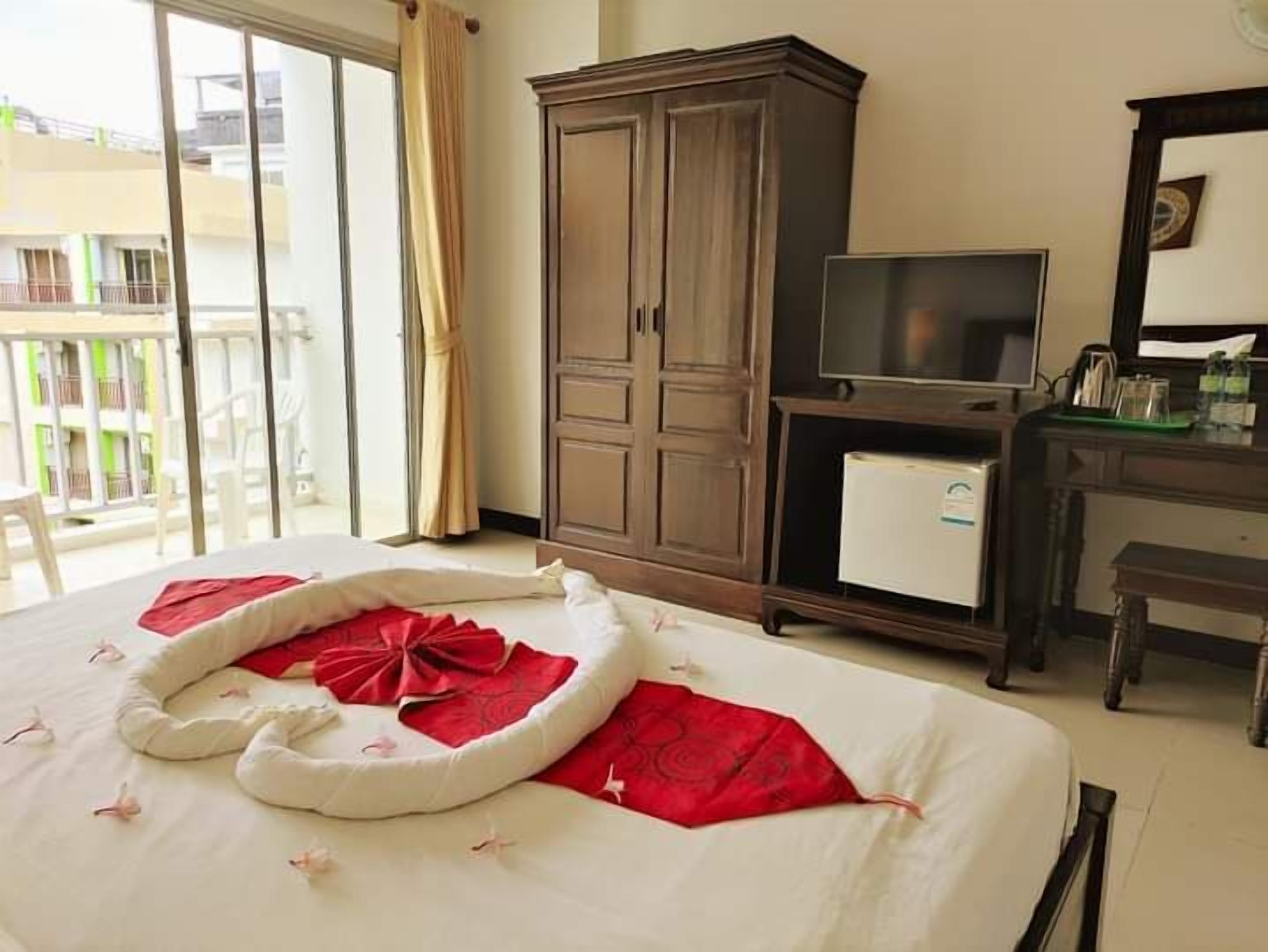 Een hotelkamer met een bed, een kledingkast, een bureau met een computer en een televisie.