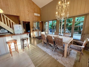 A wooden-paneled room with a dining table and chairs, a chandelier, and large windows. - Top located Cap Ferret style villa + Jacuzzi A0379 (Lège-Cap-Ferret)