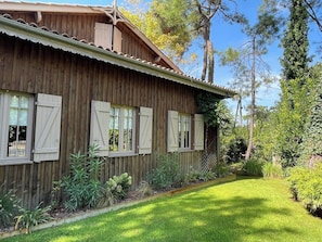 A wooden building with shutters, a lawn, and surrounding vegetation. - Top located Cap Ferret style villa + Jacuzzi A0379 (Lège-Cap-Ferret)