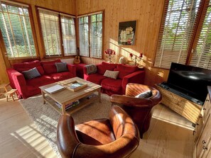 A cozy living room with a red sectional sofa, a wooden coffee table, and a leather armchair. - Top located Cap Ferret style villa + Jacuzzi A0379 (Lège-Cap-Ferret)