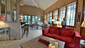 Una sala de estar acogedora con un sofá rojo, una mesa de centro de madera y un comedor con una cocina al fondo.