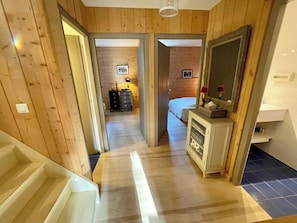 Interior em madeira com escada que leva a um quarto.