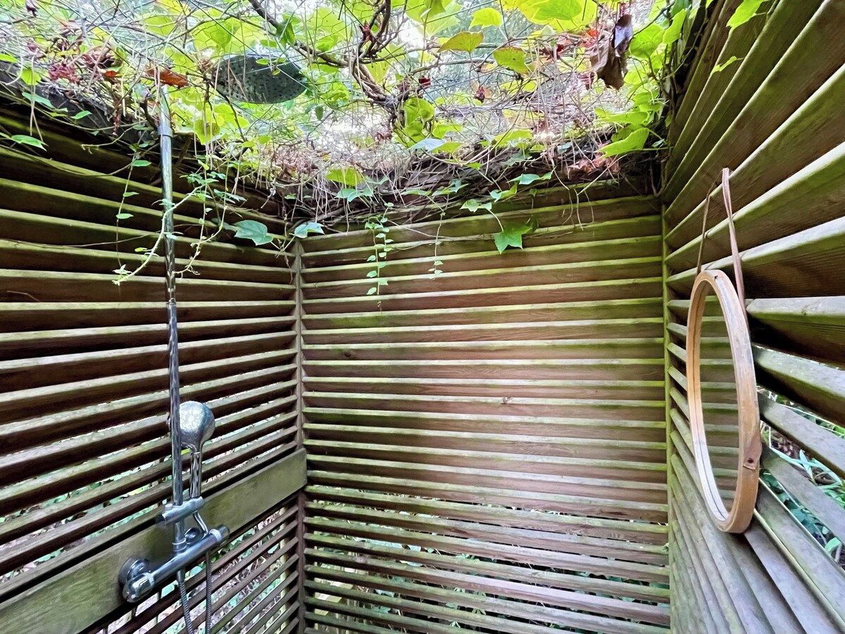 A wooden structure with horizontal slats, a metal pipe, and a circular object on the right.