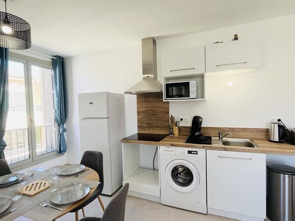 A compact kitchen with a washing machine, a microwave, and a sink.