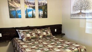 Un dormitorio con una cama grande, cabecera de madera y tres cuadros de paisajes en la pared.