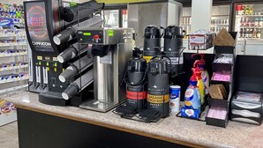 Una estación de café con una máquina de café, varios dispensadores de café y una variedad de cápsulas y botellas de café.
