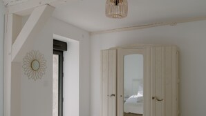 A room with a large wardrobe, a mirror, and a ceiling light fixture.