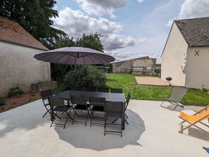 Relax in the serene outdoor patio area with a table, chairs, and lush garden.