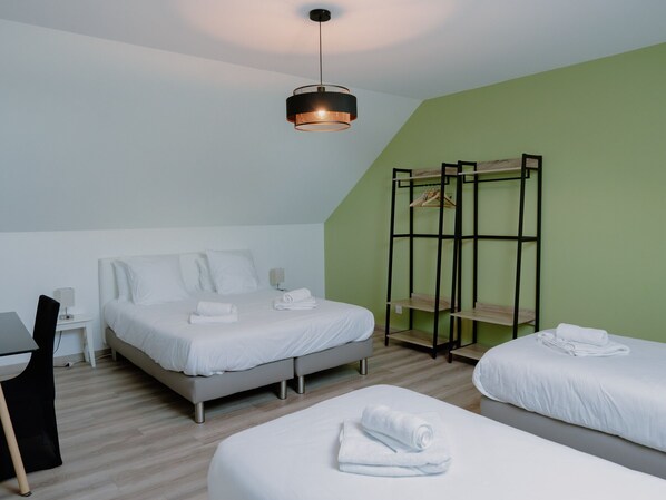 A bedroom with a bed, bedside tables, a desk, and a hanging rack.