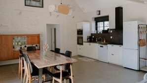 A modern kitchen with white cabinets, a wooden dining table, and black chairs.