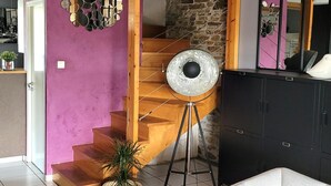 A staircase with a wooden finish, a stone wall, and a purple wall with a mirror. - Countryside cottage with pets allowed, private terrace (Tartaras)