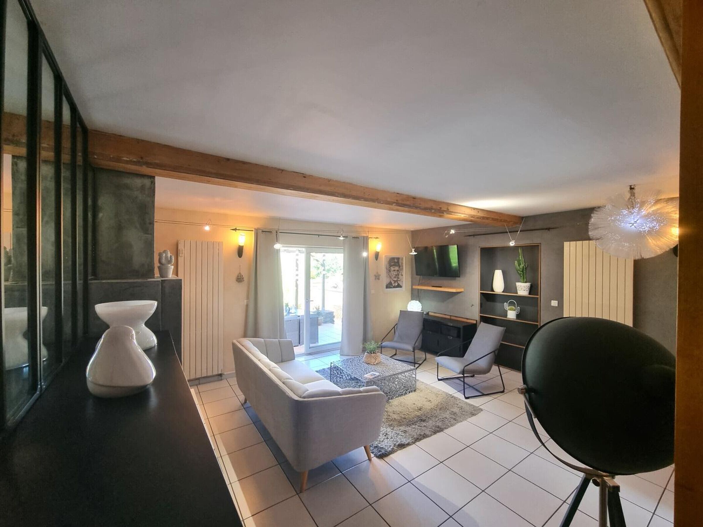 A modern living room with a sofa, chairs, a TV, and a large window.