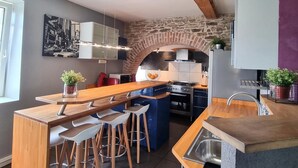 A modern kitchen with a stone arch, wooden bar, and bar stools. - Countryside cottage with pets allowed, private terrace (Tartaras)
