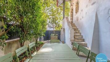 Un étroit sentier mène à un banc d’où l’on peut admirer un escalier en pierre et un bâtiment blanc.