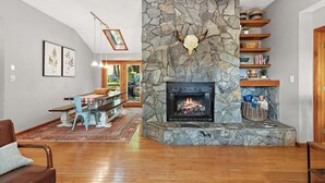 A living room with a stone fireplace, wooden shelves, and a dining area with a table and chairs. - Front Porch Therapy - Escape to your hideaway only 6 minutes above Boone (Boone)
