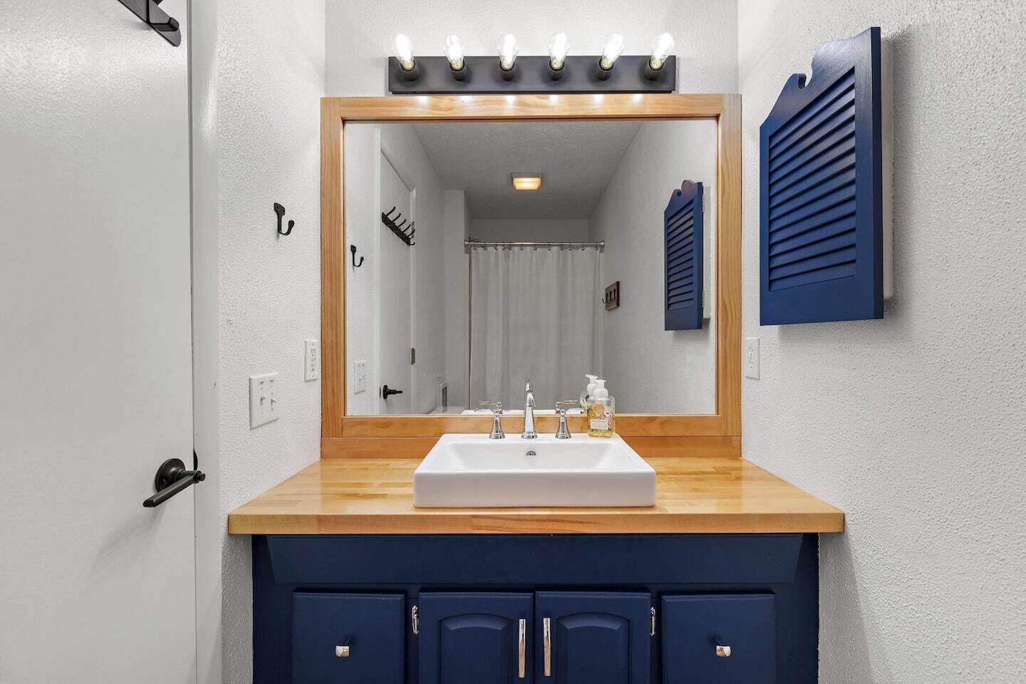 Une salle de bain avec un grand miroir, un lavabo et un meuble-lavabo avec des placards.
