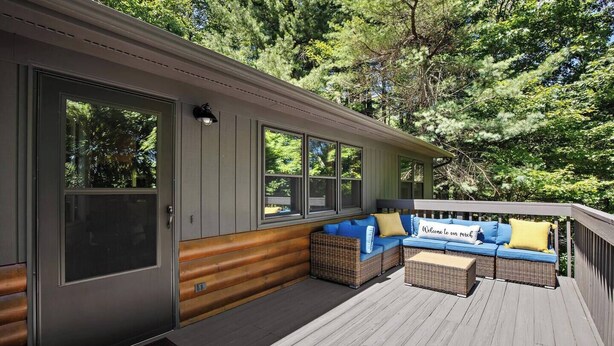A covered deck with a sofa and cushions, a door, and windows overlooking a wooded area. - Front Porch Therapy - Escape to your hideaway only 6 minutes above Boone (Boone)