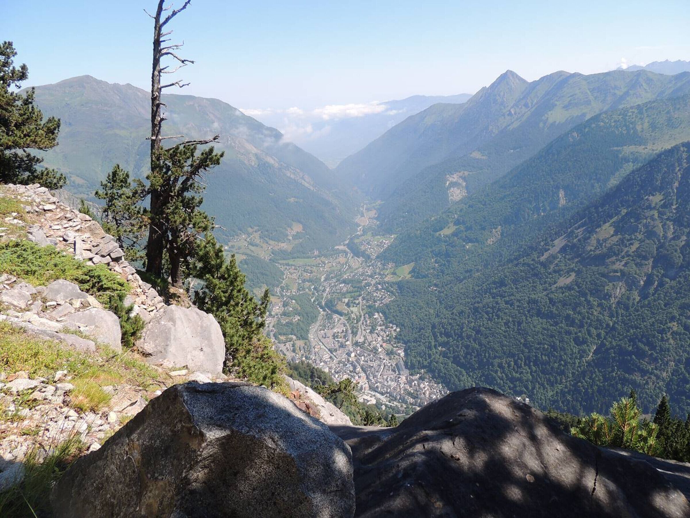 A mountainous landscape with a valley, rocky terrain, and sparse vegetation.