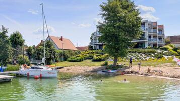 Un port de plaisance avec des bateaux, une plage de sable et des bâtiments modernes en arrière-plan.