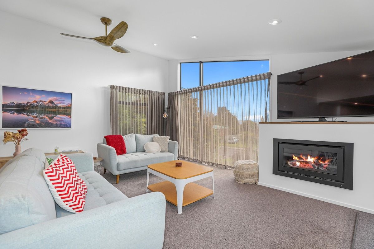 A modern living room with a fireplace, a sofa, a coffee table, and a television.