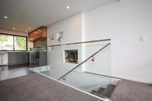 A modern kitchen with a glass staircase leading to a living area. - Redwoods Getaway - 100m to the Trails, Sleeps 7 (Rotorua)