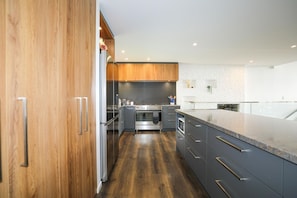 A modern kitchen with wooden cabinets, stainless steel appliances, and a granite countertop. - Redwoods Getaway - 100m to the Trails, Sleeps 7 (Rotorua)