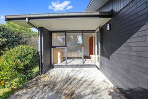 A modern house with a glass door entrance, a covered porch, and a brick exterior wall. - Redwoods Getaway - 100m to the Trails, Sleeps 7 (Rotorua)