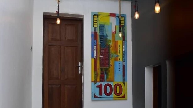 A staircase with teal steps leading to a wooden door, a colorful poster on the wall, and hanging light fixtures. - Lost & Found Dooms (Zanzibar Town)